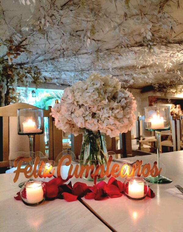 Mesa con centro de hortensias, velas y letrero de feliz cumpleaños