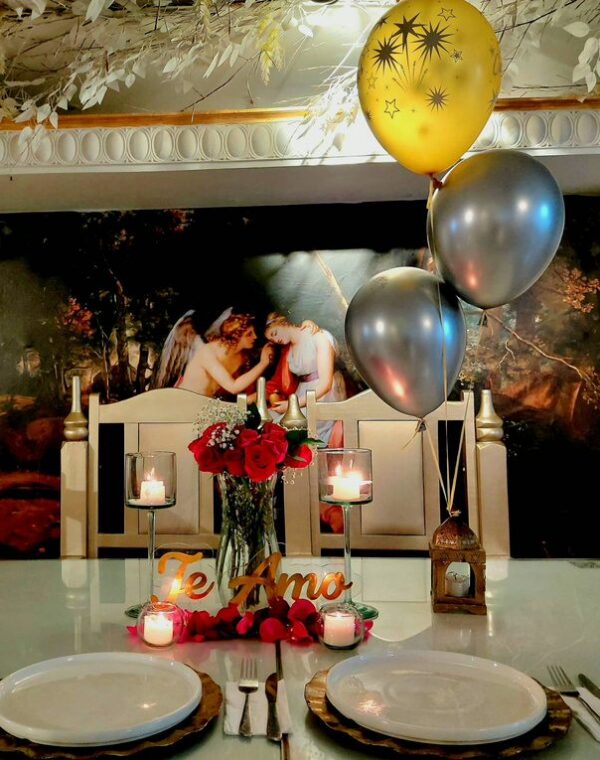 Mesa decorada con globos en helio, centro de rosas, velas y letrero de te amo