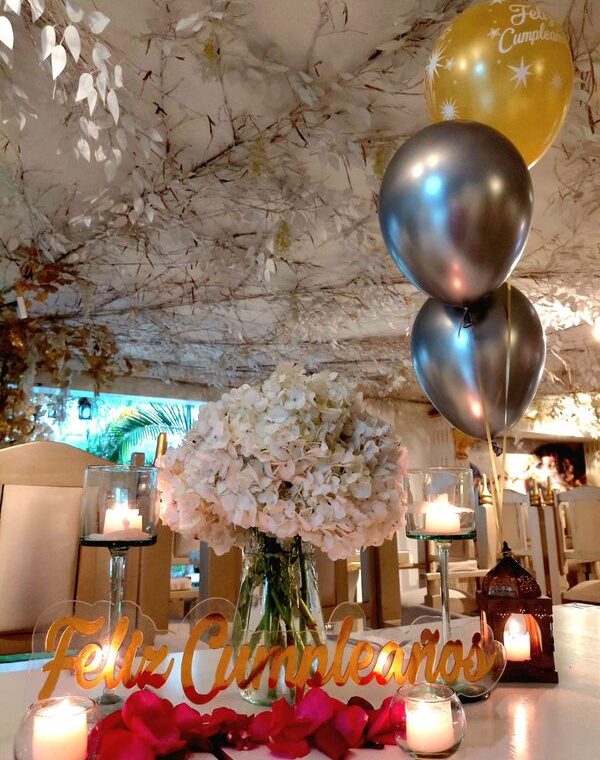 Mesa con globos en helio, centro de hortensias y letrero de feliz cumpleaños