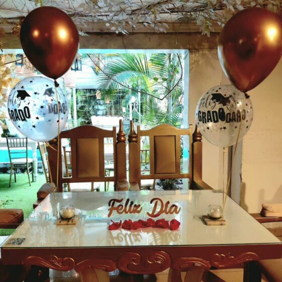 Mesa con globos de grado y letrero de feliz día