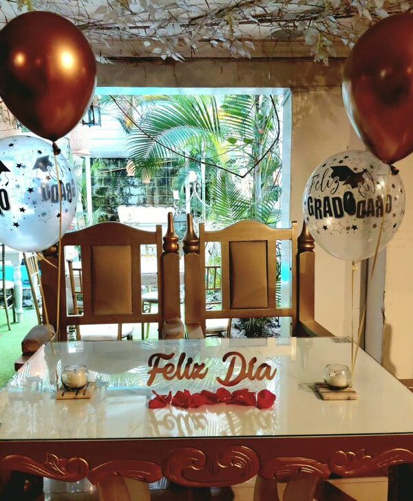 Mesa con globos de grado y letrero de feliz día