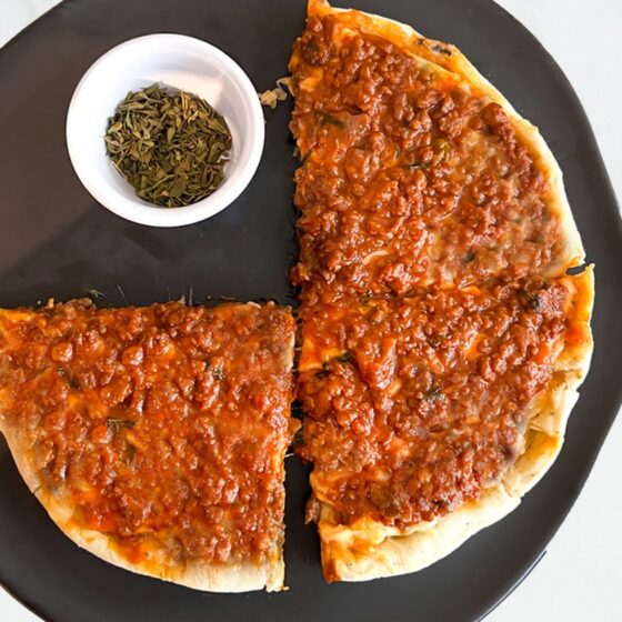 Pizza boloñesa sobre tabla negra