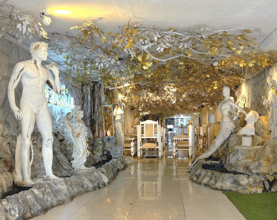 Salón de Celestial con estatuas clásicas blancas bajo un techo de hojas doradas